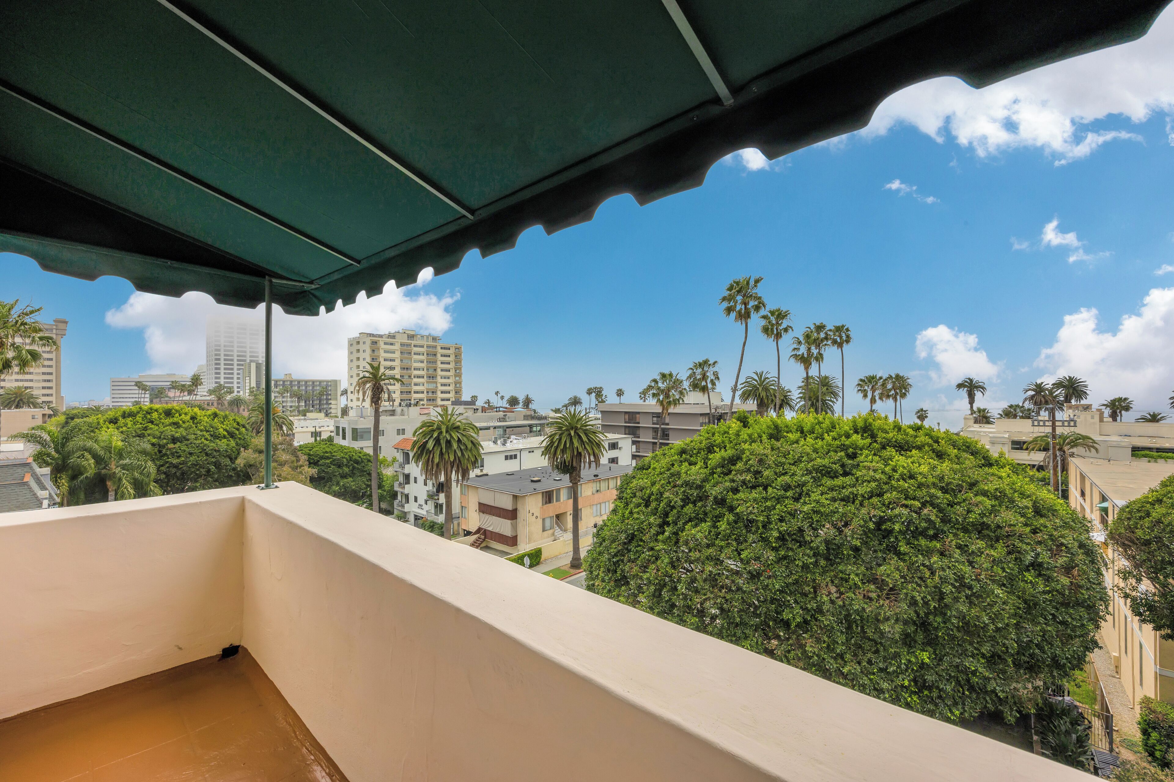 Un balcon avec vue sur les palmiers et les immeubles.