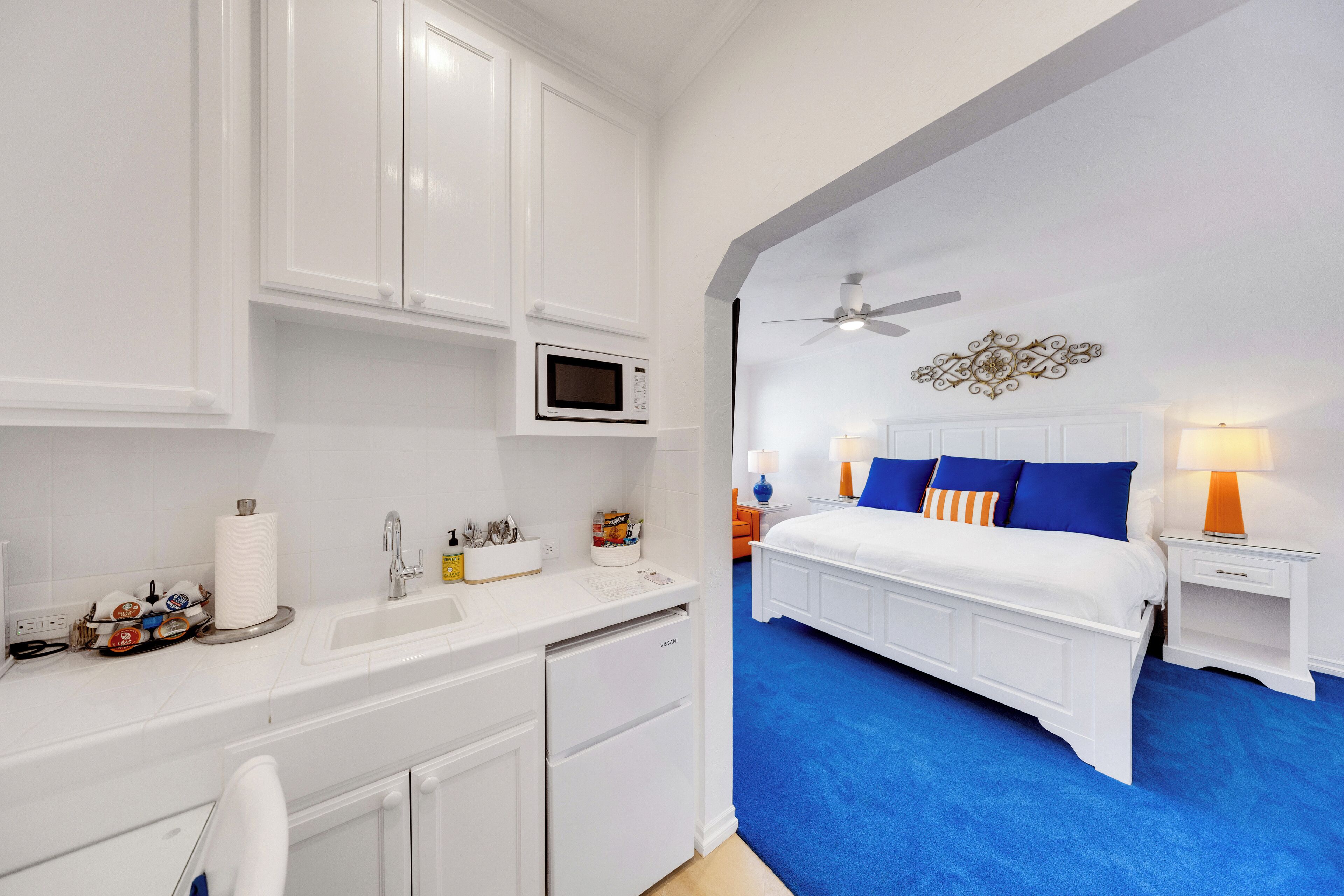 A bedroom with a bed, nightstands, a ceiling fan, and a wall-mounted TV.