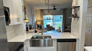Uma cozinha moderna com armários brancos, eletrodomésticos de aço inoxidável, uma ilha grande e vista para o exterior.