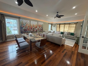 A spacious living area with a dining table, sofa, and a ceiling fan.