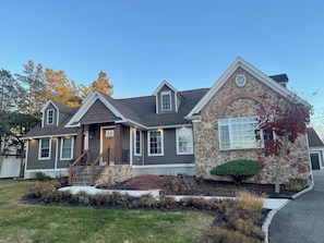 A two-story house with a stone facade, a front porch, and a well-maintained lawn.