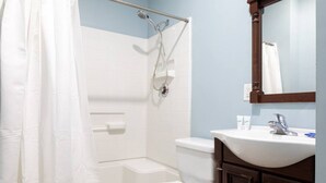 Une salle de bain équipée d’une douche, de toilettes, d’un lavabo et d’un miroir.