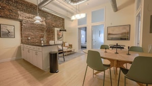 A modern kitchen with a brick wall, wooden cabinets, and a dining area with a table and chairs. - Simple & Spacious Apartment! (Boston)