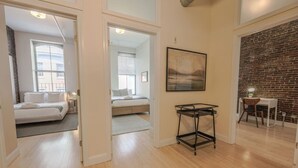 A spacious room with a large bed, a desk with a chair, and a brick wall. - Simple & Spacious Apartment! (Boston)
