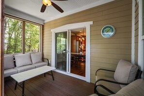 A covered porch with a sliding glass door, a sofa, a table, and a chair. - Cherry Blossom House FREE Golf Cart for entire Stay in Summer Months! (South Haven)