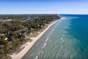An aerial view of a coastal area with a beach, houses, and a clear blue ocean. - Cherry Blossom House FREE Golf Cart for entire Stay in Summer Months! (South Haven)