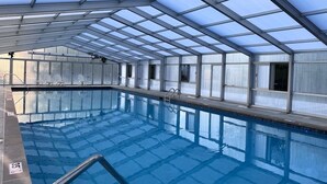 Una piscina interna con soffitti in vetro trasparente e pavimento piastrellato.