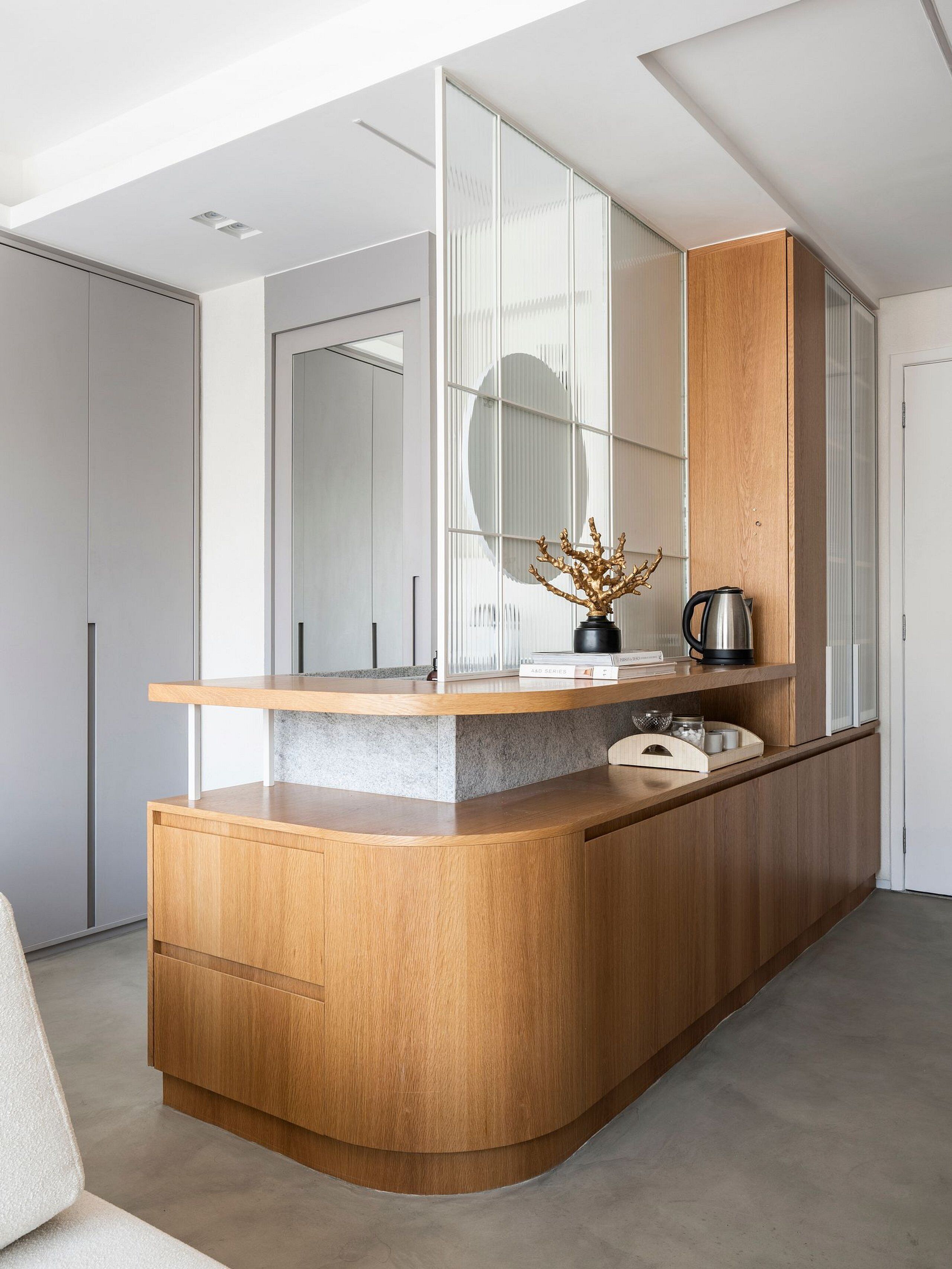 A modern kitchen with a wooden island, a coffee maker, and a vase with branches.