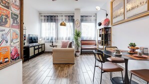 Una sala moderna con sofá, televisión y comedor con sillas y mesa.