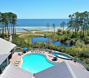 A resort with a large pool, lounge chairs, and a view of the ocean.