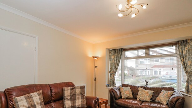 A living room with two brown leather sofas, a floor lamp, and a window with curtains. - Lavender Harmony House (Swindon)