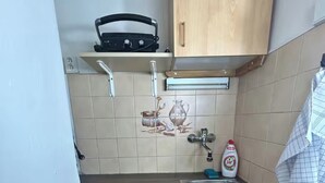 Et lille køkken med en vask, komfur og et skab over bordet.