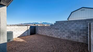 A covered outdoor area with a gravel floor, surrounded by walls and a building in the background.