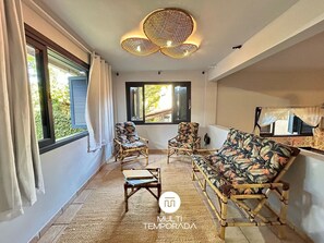 A room with a sofa, two armchairs, a small table, and a ceiling light fixture. - Canto das Praias - Florianópolis - SC (Florianópolis)