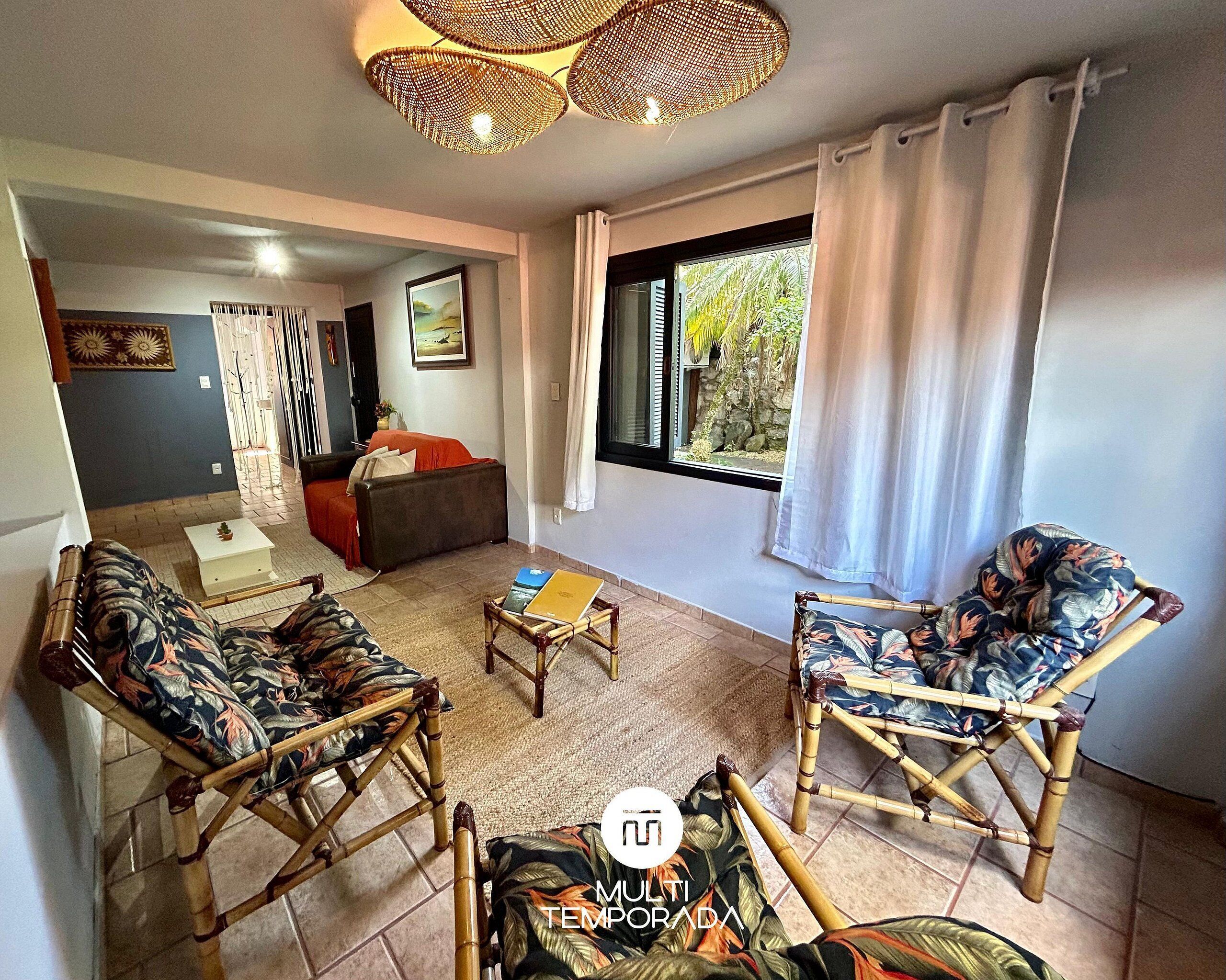 A living room with a sofa, two armchairs, a coffee table, and a window with curtains.