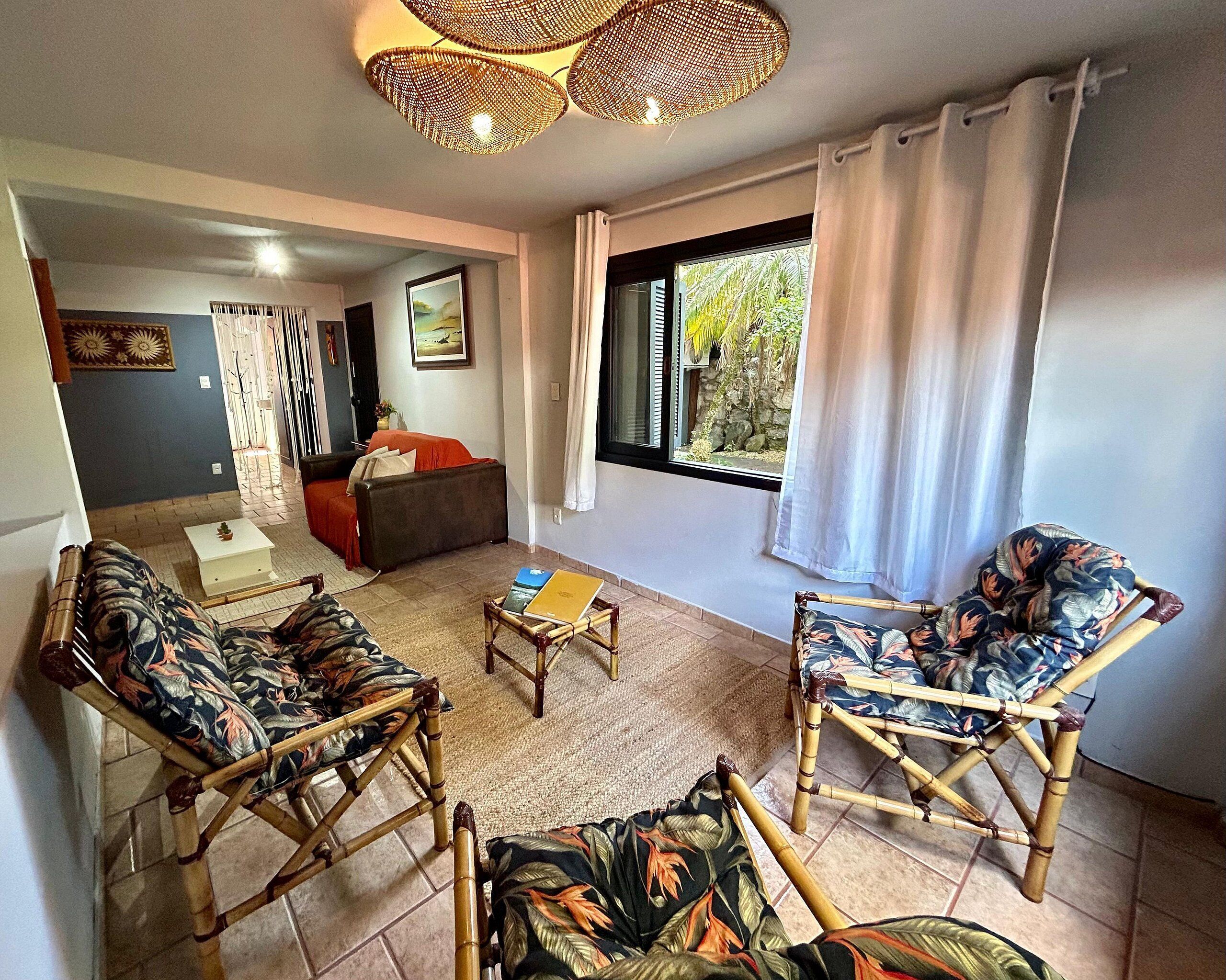 A living room with a sofa, two armchairs, a coffee table, and a window with curtains.