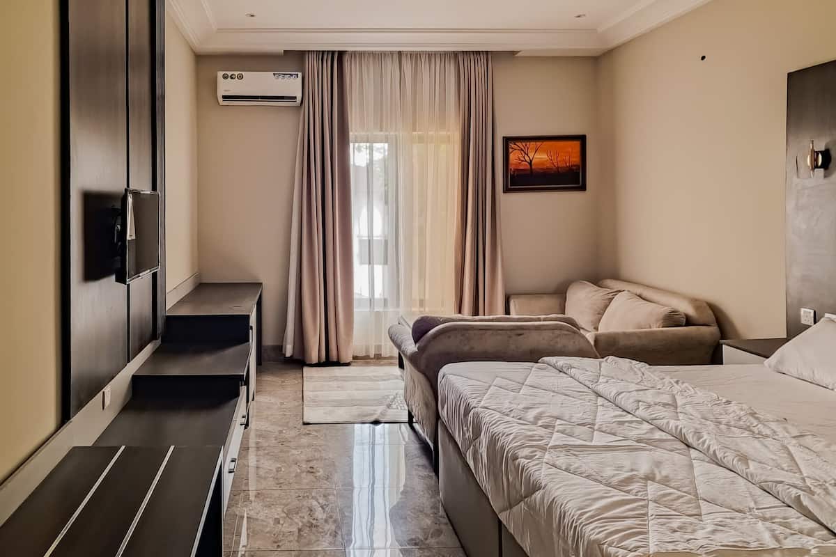 A modern bedroom with a bed, bedside tables, a TV, and a window with curtains.