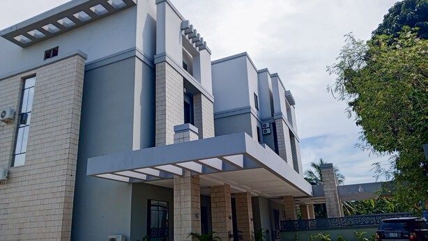 A modern building with a covered entrance, large windows, and a paved driveway. - MARVEL HOTEL & SUITES LIMITED (Port Harcourt)