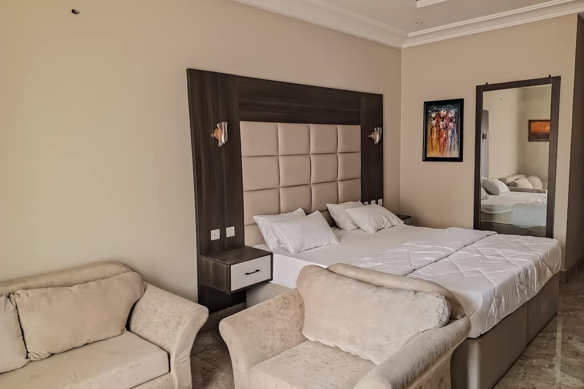 A bedroom with a large bed, two bedside tables, a nightstand, a sofa, and a chair.