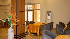A conference room with a long table and chairs, a vase with flowers, and a door with an exit sign. - MARVEL HOTEL & SUITES LIMITED (Port Harcourt)