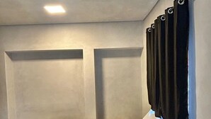 Ein Schlafzimmer mit einem Bett, einer schwarzen Tagesdecke und einem weißen Kopfkissen.