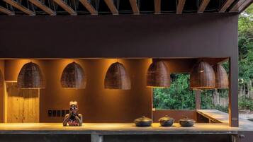 Una cocina moderna con encimera de hormigón, lámparas colgantes de fibra natural y un banco de madera.