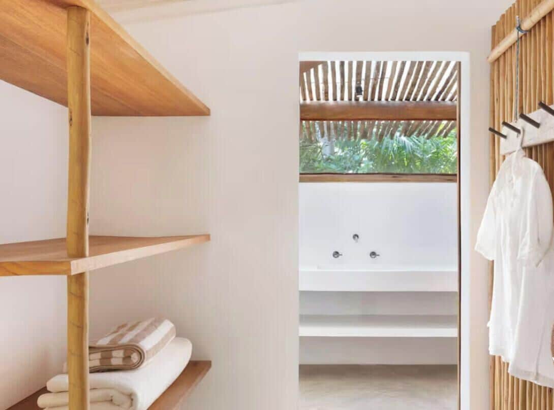 Un baño moderno con un estante de madera, una bañera y un perchero para toallas.