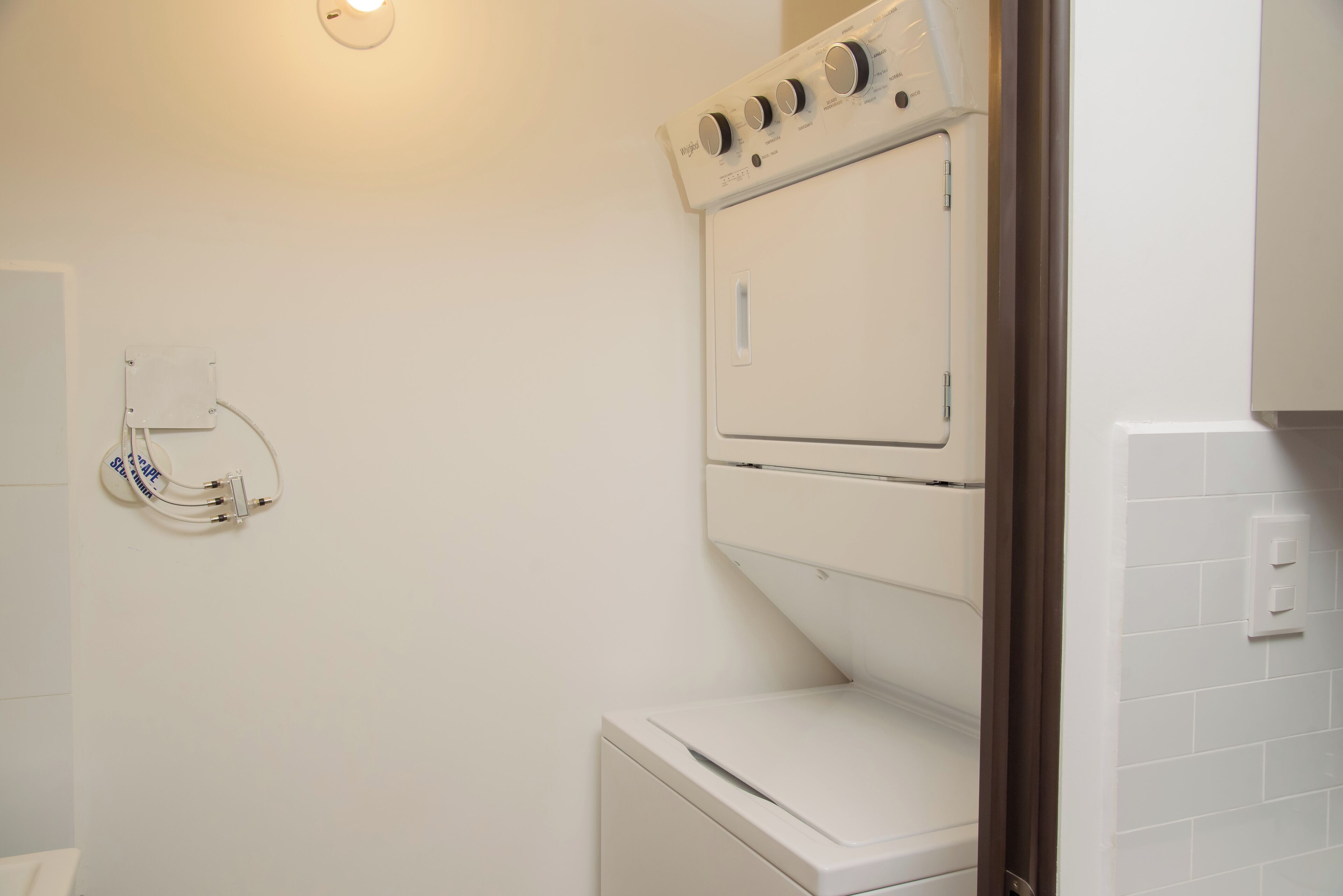 A laundry area with a washing machine and dryer, a wall-mounted electrical outlet, and a light fixture.