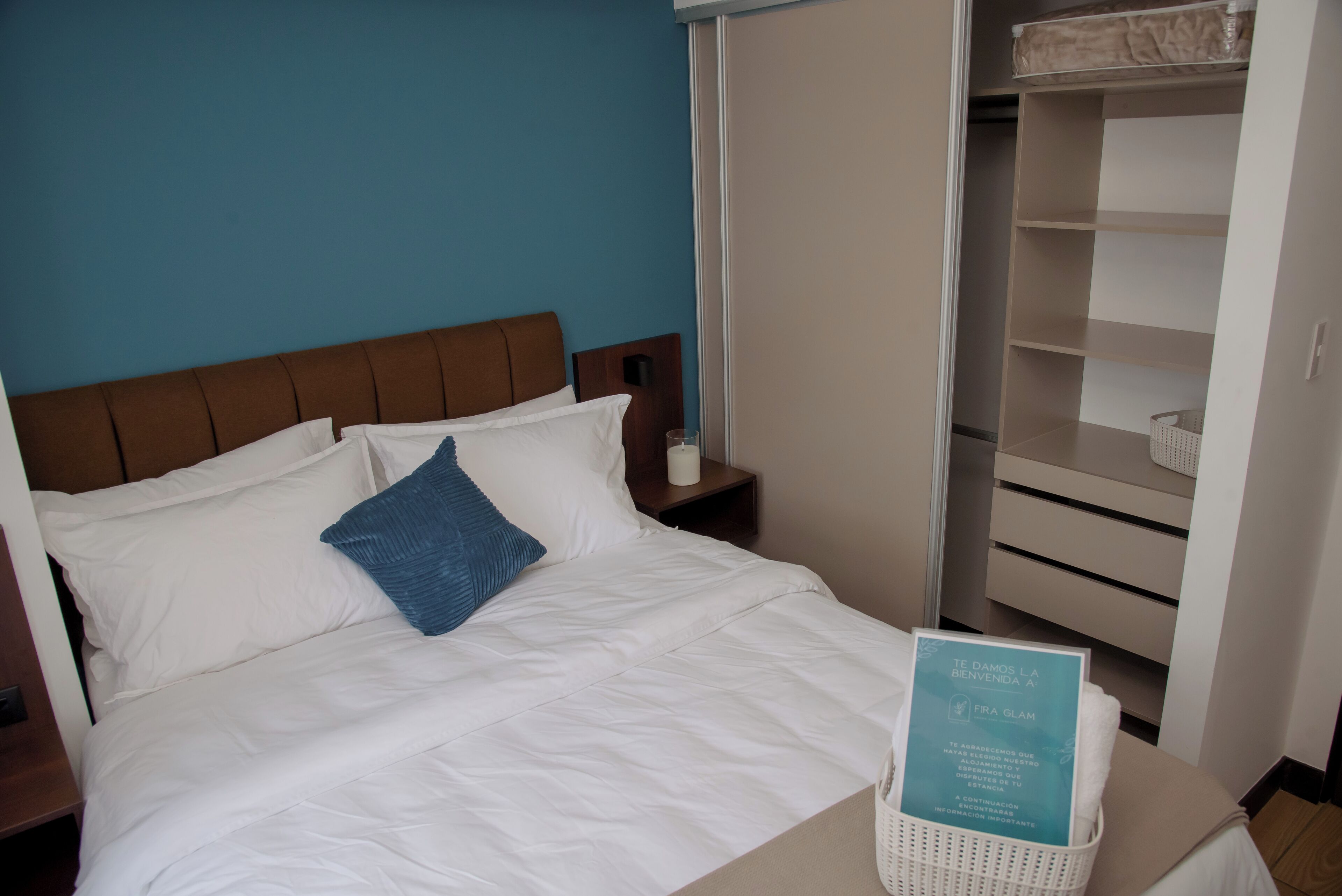 Une chambre d’hôtel avec un lit, une table de chevet, une armoire et un panneau d’accueil.