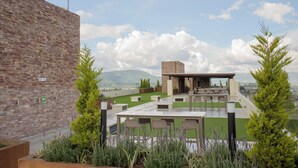 A rooftop terrace with a bar area, seating, and a view of mountains. - Glam | Modern apartment in exclusive area of Xela (Quetzaltenango)