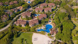 Ein Resort mit mehreren Gebäuden, einem großen zentralen Pool und einem Strandbereich.
