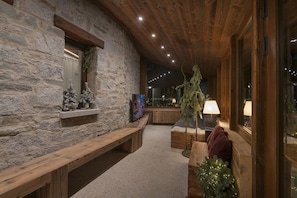 A cozy interior with stone walls, wooden benches, and a television. - Charme mountain Chalet (Ponte di legno)