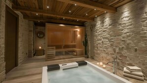 Et spa-område med stenvæg, træloft og sauna med glasvægge.