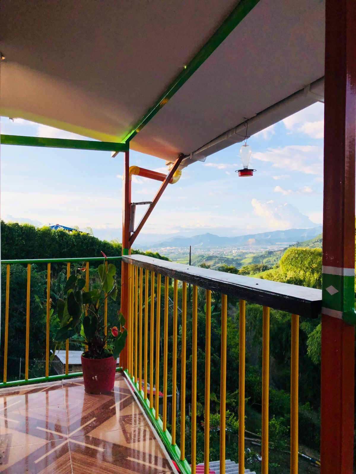 A balcony with a view of a green landscape and mountains.