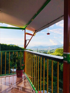 A balcony with a view of a green landscape and mountains.