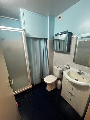 Et badeværelse med toilet, håndvask og bruser.