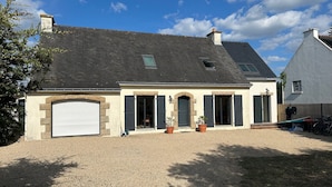 Une maison à deux étages avec une allée gravillonnée, un garage et une cour clôturée.