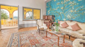 A spacious living room with a large window, a sofa, a coffee table, and a decorative rug.