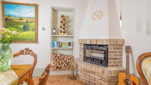 Uma sala de estar acolhedora com lareira, estante de livros, um violão e um quadro.