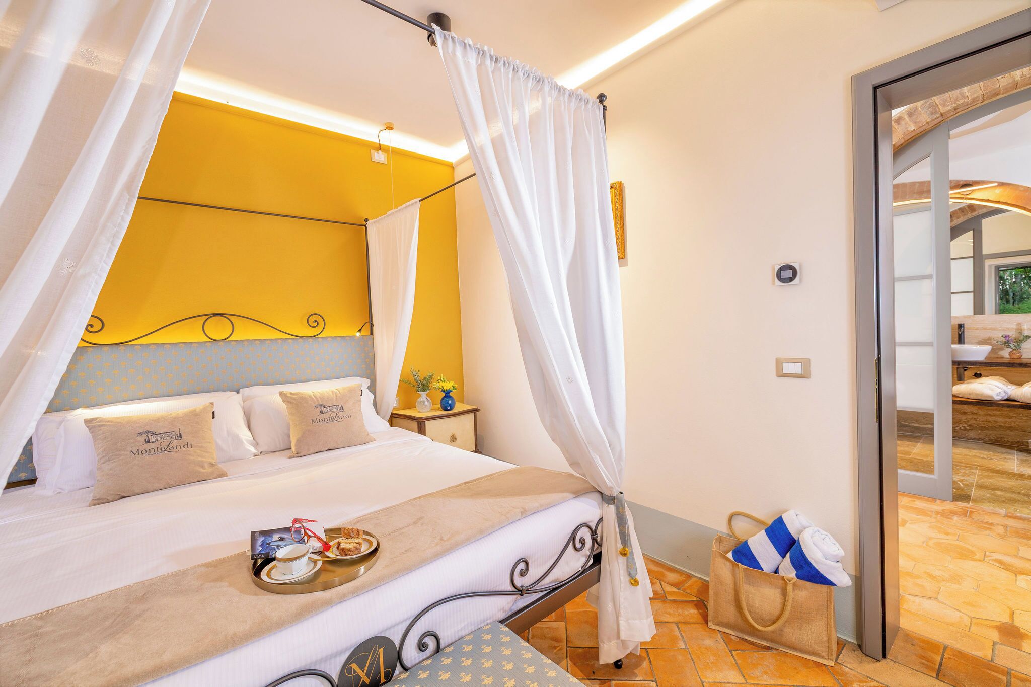 Een hotelkamer met een bed, nachtkastje en badkamer zichtbaar door een geopende deur.