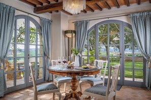 Un comedor con una mesa redonda, sillas y vistas a un campo de golf a través de grandes ventanales.