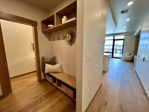 A hallway with a bench, shelves with books, and a hat on the wall. - Clubhouse & Pool Amenities, 40 Mins to Glacier NP (Whitefish)