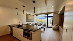 Eine moderne Küche mit Kochinsel, integriertem Backofen und einem Essbereich mit Sofa und Stuhl.