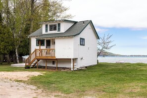 Une maison de plain-pied avec une terrasse à l’avant, un petit porche et une vue sur un lac.
