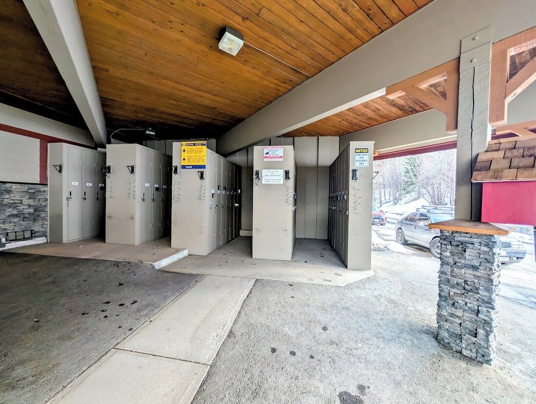 A covered area with multiple doors, a stone pillar, and a wooden ceiling.