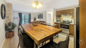 Una cocina moderna con una mesa de comedor de madera, sillas negras y electrodomésticos de acero inoxidable.