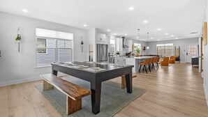Cozinha moderna com ilha central, piso de madeira e área de refeições com cadeiras.