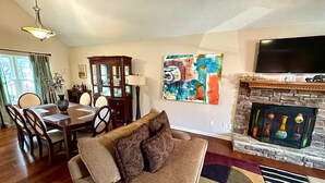 A living room with a sofa, a fireplace, a dining area, and a TV. - Quiet, charming 4-bedroom house; 20mins from Atlanta & Airport. (Lithia Springs)