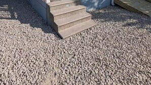 Ein kleines, eingeschossiges Haus mit einer Veranda, einer Treppe zum Eingang und einem Schotterweg.