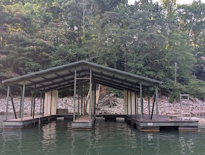 A covered dock with a wooden structure and a stone wall in the background.